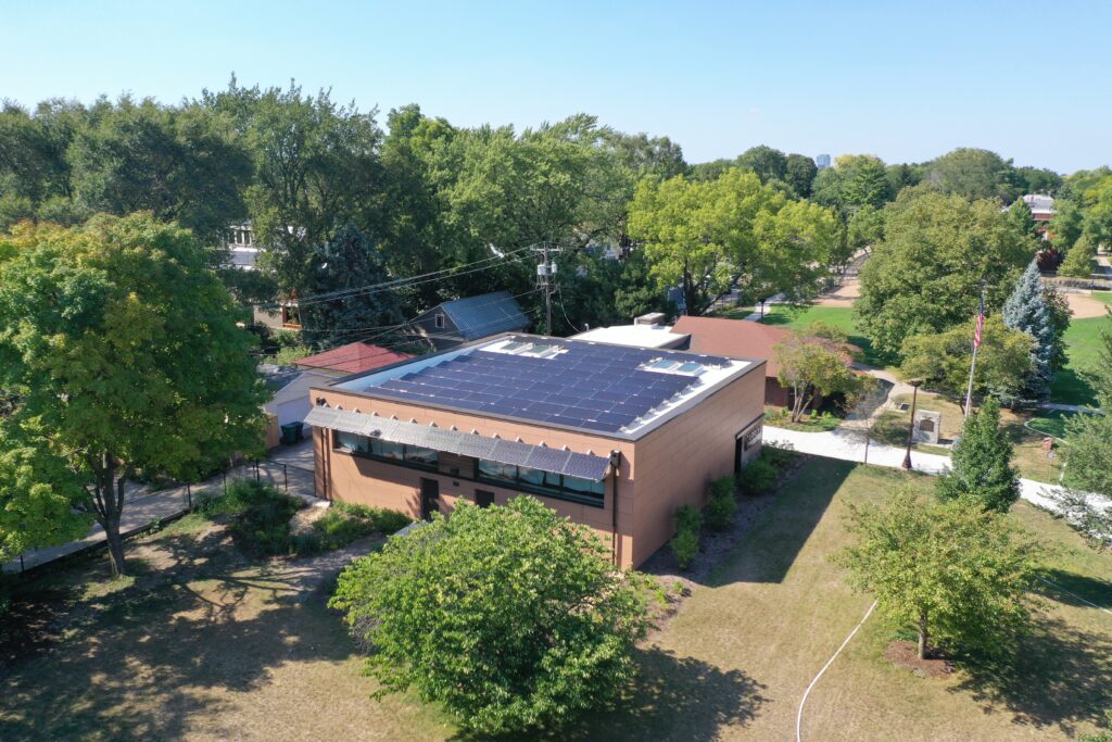 Aerial view of a building with solar panels on the roof surrounded by trees and green space, illustrating the benefits of solar energy systems in industrial parks.